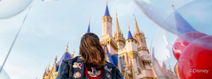 Girl surrounded by balloons looking up at Disney World castle